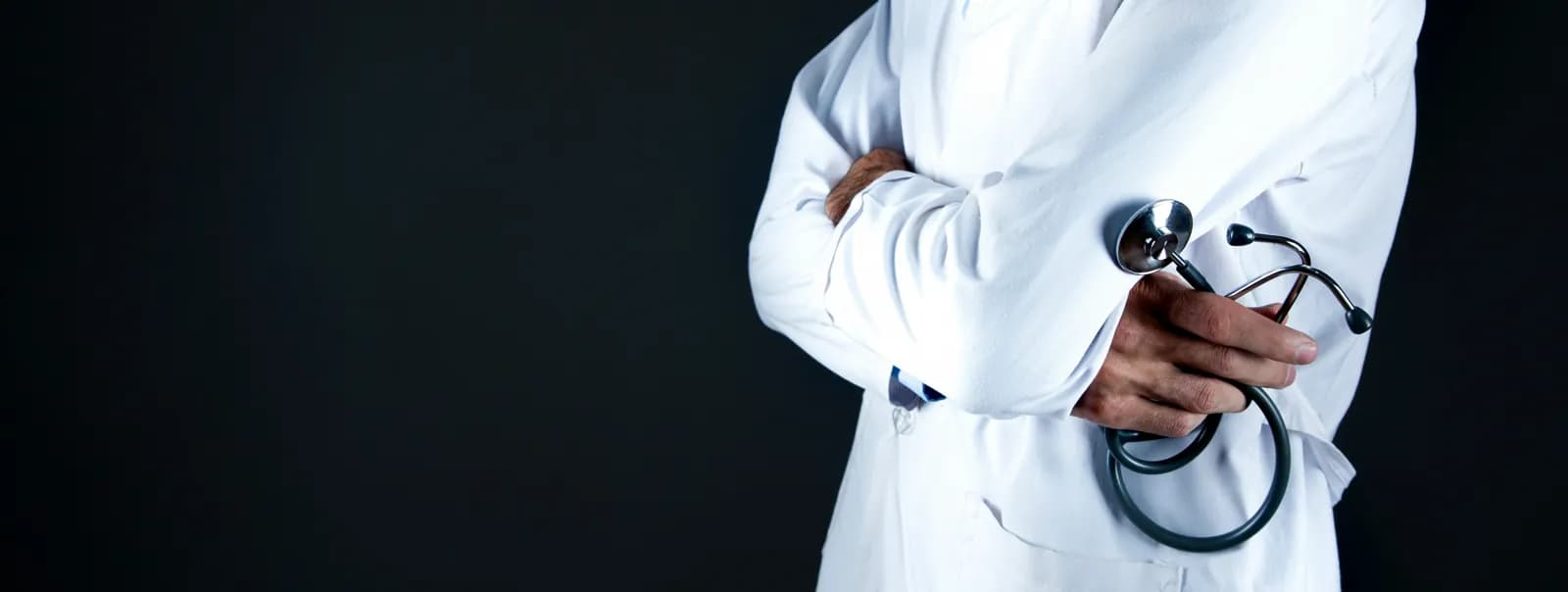 A doctor in a white coat with arms crossed, holding a stethoscope